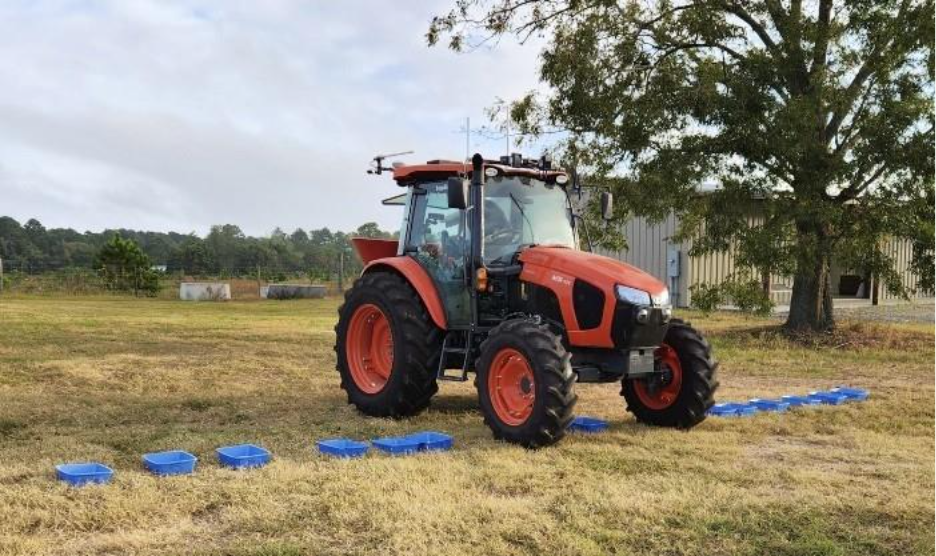 Tractor with spreader driving over catch pans for spreader calibration.